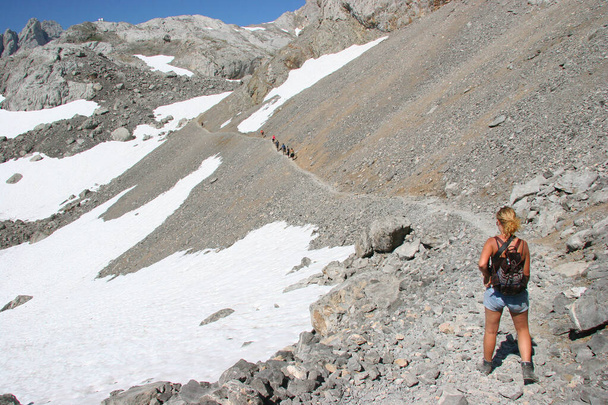girl hiking through snow on mountain slope trail, with backpack and mountain shoes - Photo, Image