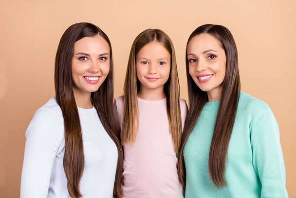 Portrait of three attractive tender cheerful girls hugging trust feelings isolated over beige pastel color background - Foto, imagen