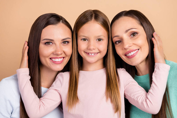 Portrait of three attractive cheerful tender sweet affectionate girls bonding cuddling isolated over beige pastel color background - Fotografie, Obrázek