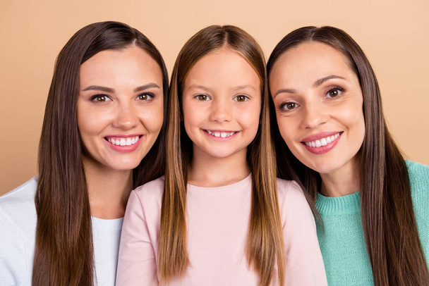 Portrait of three attractive cheerful cute affectionate girls bonding isolated over beige pastel color background - Photo, Image