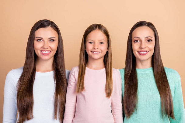 Retrato de tres atractivas chicas de pelo castaño alegres mami hija aislada sobre fondo de color pastel beige - Foto, imagen