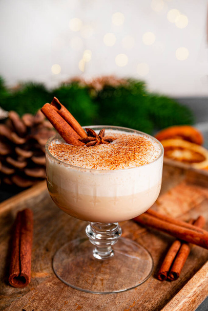 A glass of traditional Christmas drink eggnog on a table, vertical photo with copy space for text. Spicy drink made from egg and milk with cinnamon, cardamom. High quality photo - Valokuva, kuva