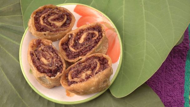 Closeup of plate with sweet pastry rolls on green leaves background  - Photo, Image