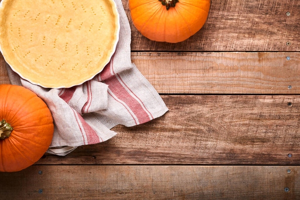 Pumpkin and food ingredients, spices, cinnamon and kitchen utencil on old rustic wooden background. Concept homemade baking for holiday. Cooking pumpkin pie and cookies for Thanksgiving day. - Foto, imagen