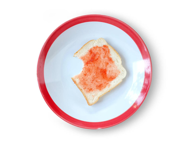 Znak ugryzień krojonego chleba natryskiwanego dżemem truskawkowym na okrągłym talerzu izolowanym na białym tle ze ścieżką wycinania. - Zdjęcie, obraz