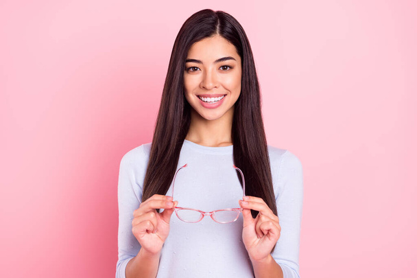 Portrait of attractive cheerful content intellectual girl holding in hands specs isolated over pink pastel color background - Foto, afbeelding