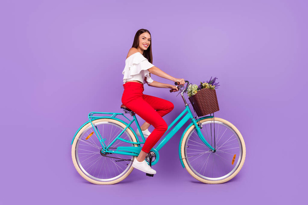Photo of cheerful lady ride bicycle spring weekend wear white blouse trousers shoes isolated purple color background - Foto, immagini