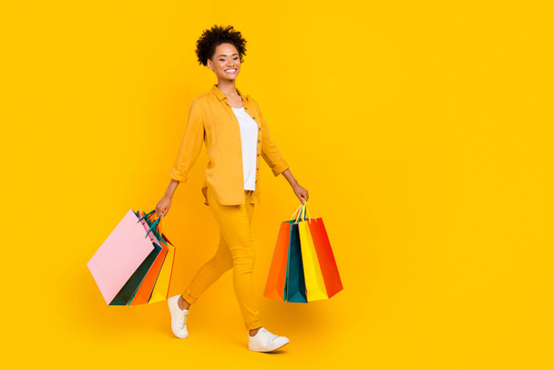 Full size profile side photo of young afro girl go walk shopping store isolated over yellow color background - 写真・画像