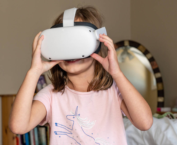Menina assistindo um aplicativo em um fone de ouvido VR moderno - Foto, Imagem