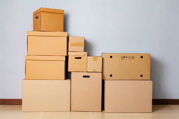 Cardboard boxes for moving on the floor against grey wall - Foto, Imagem
