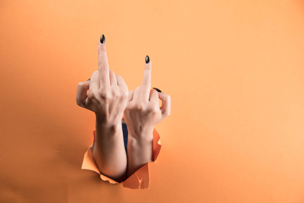 γυναικείο χέρι δείχνει μεσαίο δάχτυλο σε πορτοκαλί φόντο - Φωτογραφία, εικόνα
