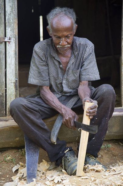old man sitting and working with wood, travel shot - Foto, afbeelding