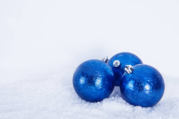 Weihnachtsgruß Hintergrund, blaue Kugeln auf weißem Schnee Hintergrund.  - Foto, Bild