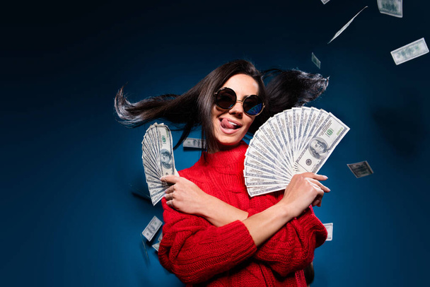 Photo of cool brown hair lady hold money tongue out wear spectacles red sweater isolated on blue color background - Foto, Imagem