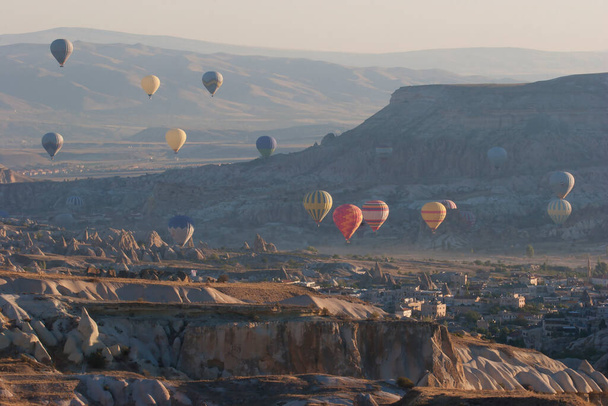дрейфующие воздушные шары с туристами, которые наслаждаются подавляющим видом на вулканический ландшафт над национальным парком - Фото, изображение