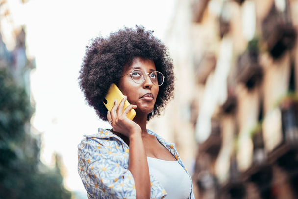 πορτραίτο μιας Αφρικάνας που μιλάει στο τηλέφωνο στο δρόμο. - Φωτογραφία, εικόνα