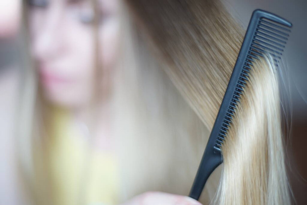 Giovane donna con una ciocca di capelli shatush da vicino. Il processo di combinazione con un pettine nero fine - Foto, immagini