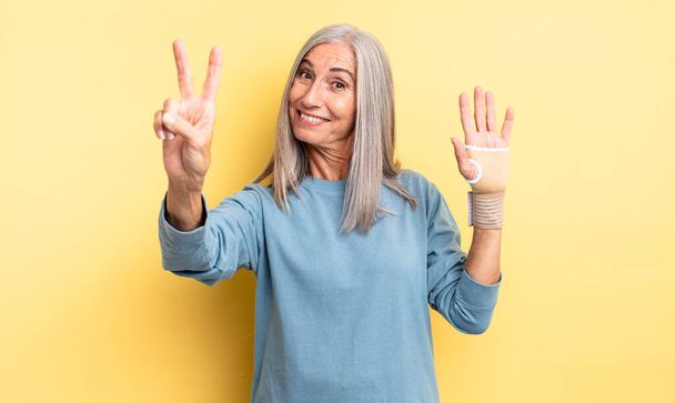 middle age pretty woman smiling and looking happy, gesturing victory or peace. hand bandage concept - Foto, afbeelding