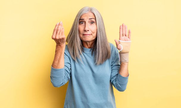 middle age pretty woman making capice or money gesture, telling you to pay. hand bandage concept - Photo, image
