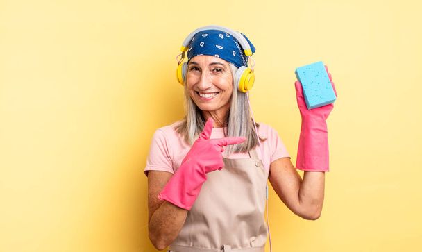 middle age pretty woman smiling cheerfully, feeling happy and pointing to the side. scourer cleaner - Foto, Imagem