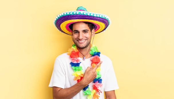 hispanic handsome man smiling cheerfully, feeling happy and pointing to the side. mexican party concept - Photo, image