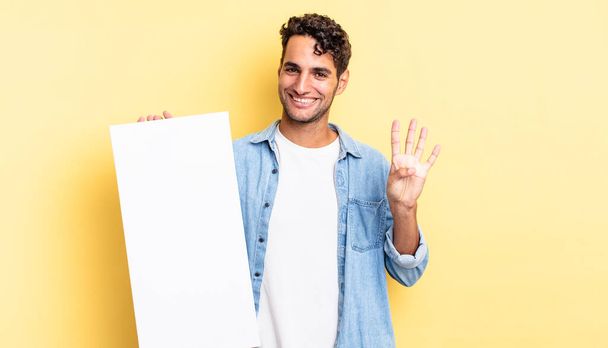 hispanic handsome man smiling and looking friendly, showing number four. empty canvas concept - Фото, зображення