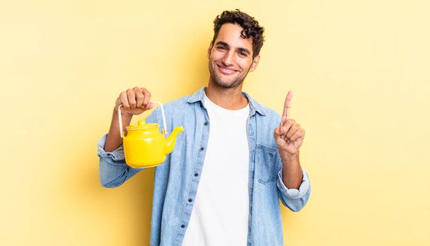 hispanic handsome man smiling and looking friendly, showing number one. teapot concept - Fotoğraf, Görsel