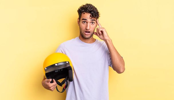 hispanic handsome man looking surprised, realizing a new thought, idea or concept. motorbike helmet concept - Foto, Imagem