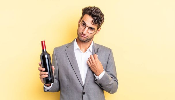 hispanic handsome man looking arrogant, successful, positive and proud. wine bottle concept - Fotoğraf, Görsel