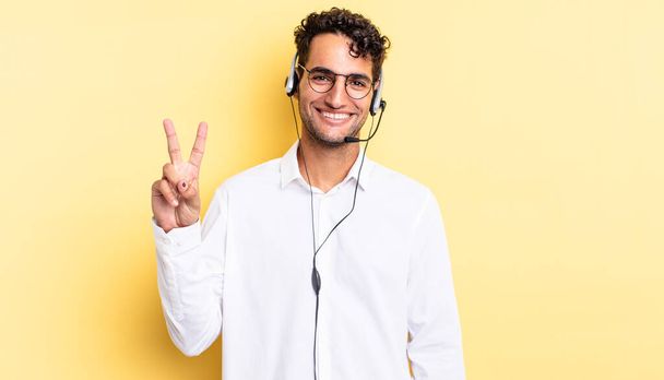 hispanic handsome man smiling and looking friendly, showing number two. telemarketer concept - Foto, Imagen