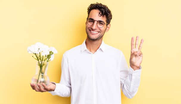 hispanic handsome man smiling and looking friendly, showing number three. flowers pot concept - Photo, image