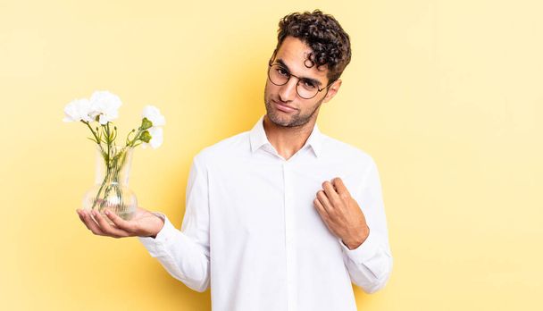 hispanic handsome man looking arrogant, successful, positive and proud. flowers pot concept - Фото, изображение
