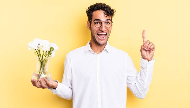 hispanic handsome man feeling like a happy and excited genius after realizing an idea. flowers pot concept - Фото, изображение