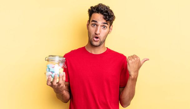 hispanic handsome man looking astonished in disbelief. candies concept - Photo, image