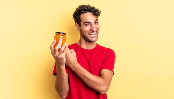 hispanic handsome man feeling happy and facing a challenge or celebrating. peach jam - Foto, afbeelding