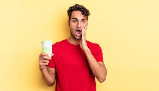 hispanic handsome man feeling shocked and scared. take away coffee concept - Photo, image