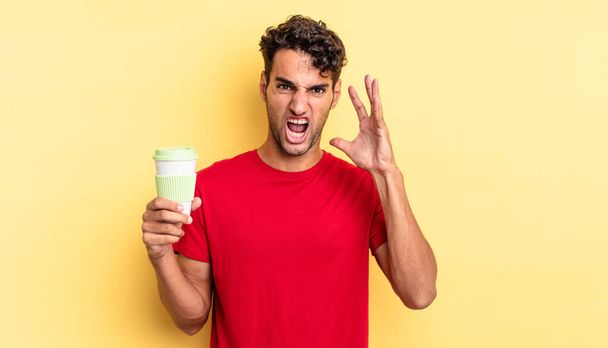 hispanic handsome man screaming with hands up in the air. take away coffee concept - Foto, afbeelding