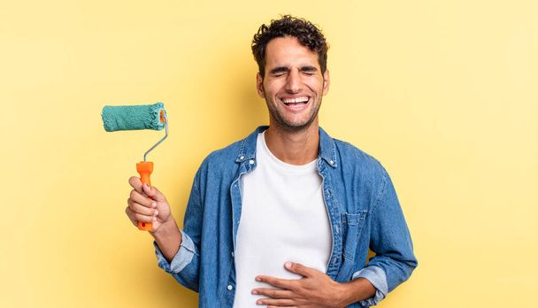 hispanic handsome man laughing out loud at some hilarious joke. roller paint concept - Photo, image