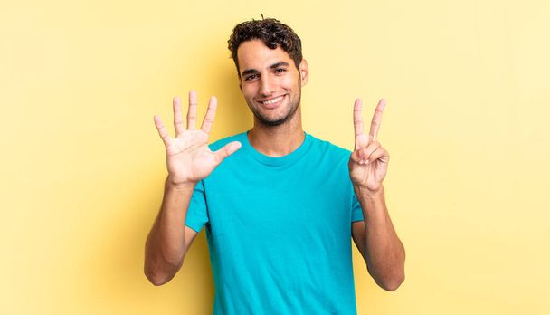 hispanic handsome man smiling and looking friendly, showing number seven - Фото, зображення