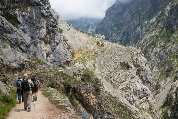 Excursionistas de montaña en una conocida ruta de senderismo a través de un estrecho y empinado desfiladero con una ruta de senderismo tallada en el norte de España. - Foto, Imagen