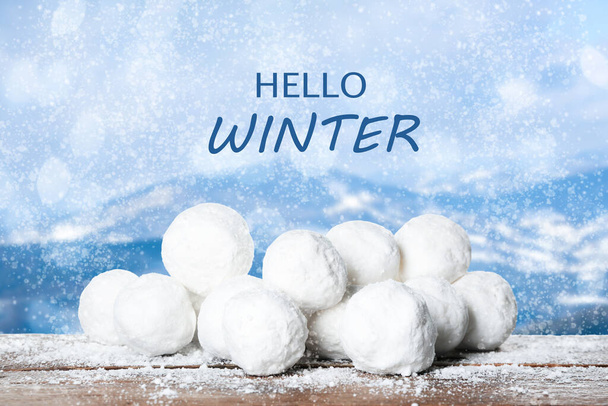 Hallo Winter. Sneeuwballen op houten oppervlak en wazig uitzicht op bergen  - Foto, afbeelding