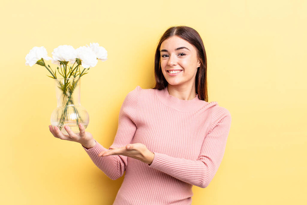 young hispanic woman smiling cheerfully, feeling happy and showing a concept. flower pot concept - Photo, Image