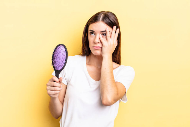 young hispanic woman feeling bored, frustrated and sleepy after a tiresome. hair brush concept - 写真・画像