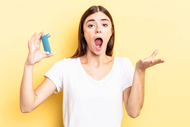 young hispanic woman feeling extremely shocked and surprised. asthma concept - Foto, afbeelding