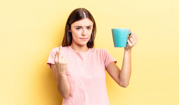 young hispanic woman feeling angry, annoyed, rebellious and aggressive. coffee cup concept - Photo, image
