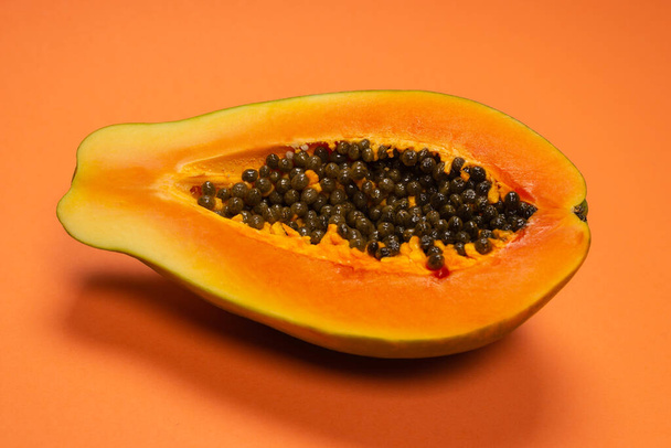 オレンジ色の背景にパパイヤの果物。熱帯果実。半パパイヤ.  - 写真・画像
