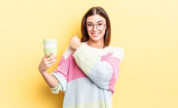 young hispanic woman feeling happy and facing a challenge or celebrating. take away coffee concept - 写真・画像