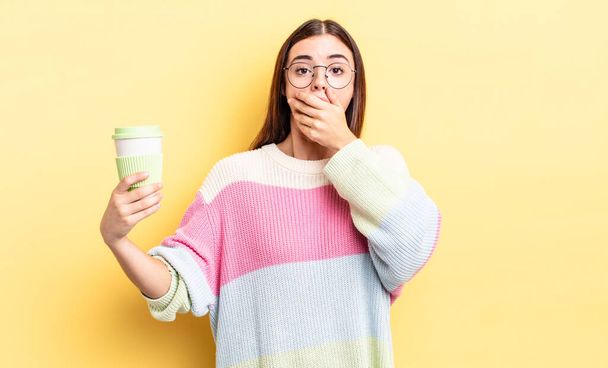young hispanic woman covering mouth with hands with a shocked. take away coffee concept - Φωτογραφία, εικόνα