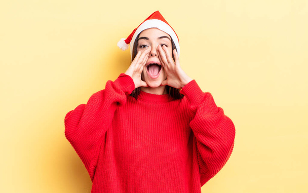young hispanic woman feeling happy,giving a big shout out with hands next to mouth. chistmas and new year concept - Zdjęcie, obraz