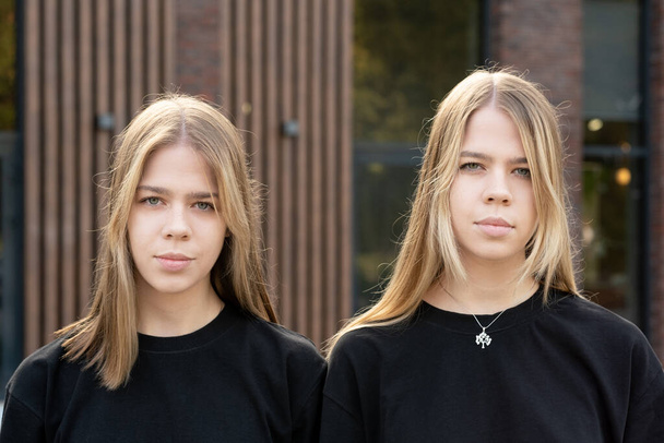 Девушки-близнецы в черных свитерах смотрят на тебя - Фото, изображение
